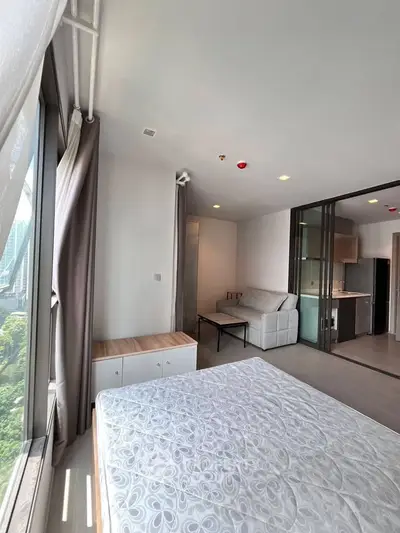 Modern studio apartment with large windows and open kitchen layout, offering a bright and airy living space.