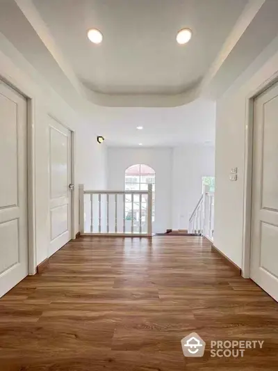 Spacious hallway with elegant wooden flooring and bright natural light