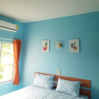 Cozy bedroom with blue walls and natural light, featuring modern decor and air conditioning.