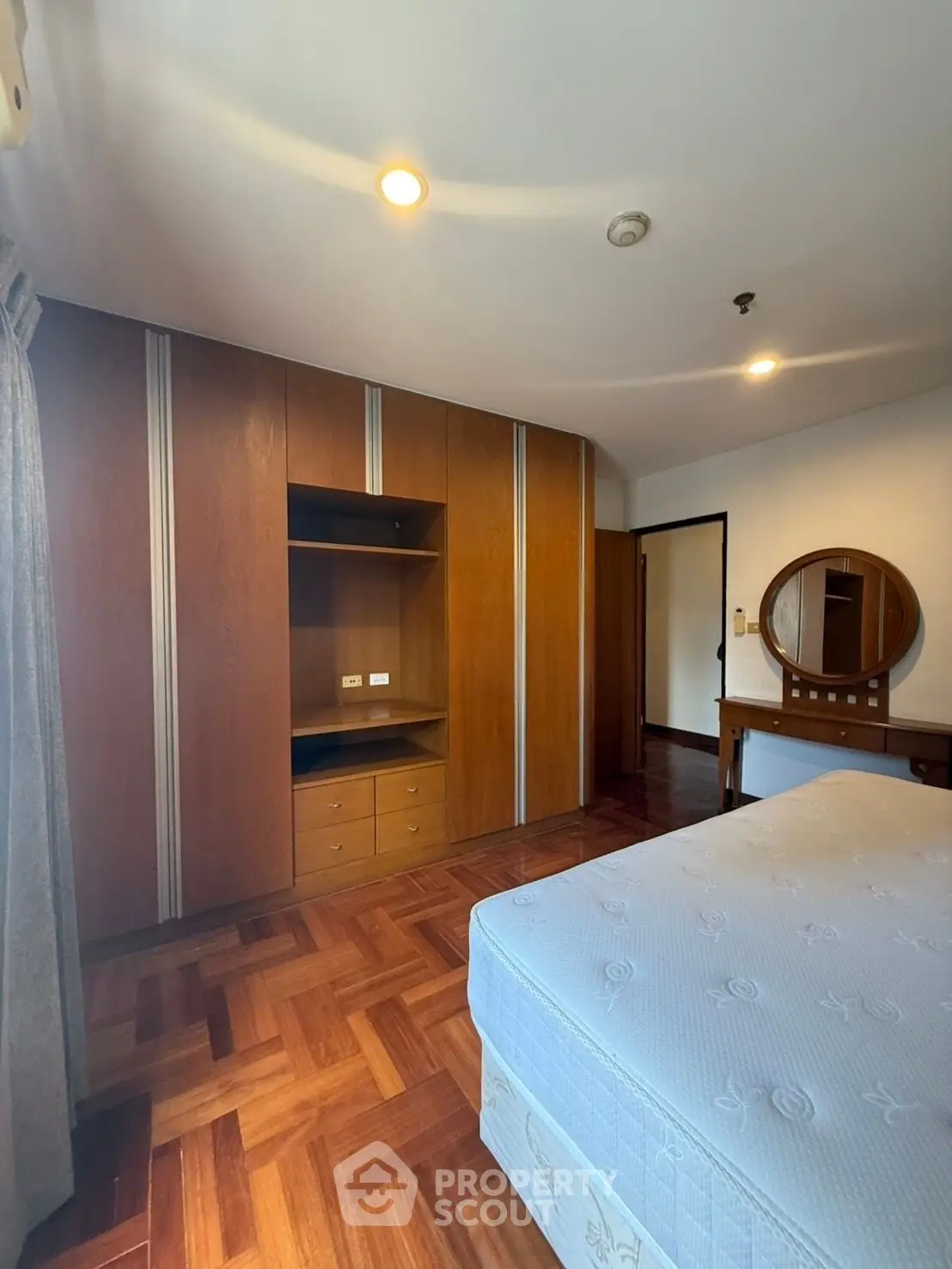 Spacious bedroom with wooden flooring and built-in wardrobe, perfect for modern living.