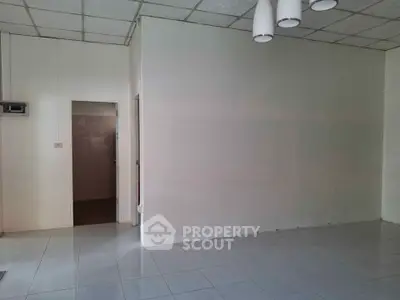 Spacious empty room with tiled floor and ceiling lights, ready for customization.