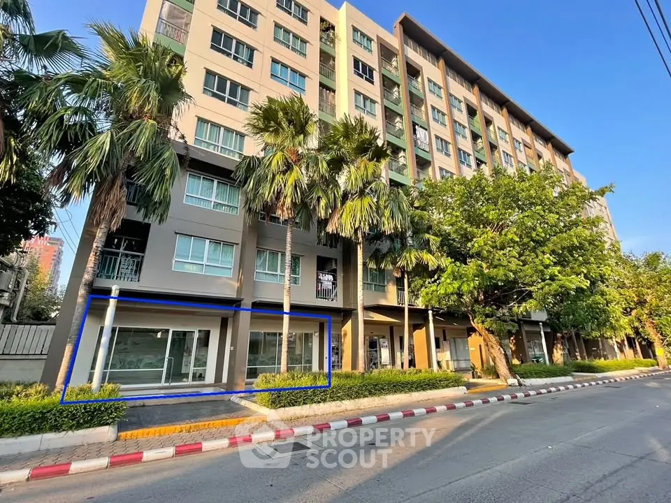 Modern apartment building exterior with lush greenery and street view.