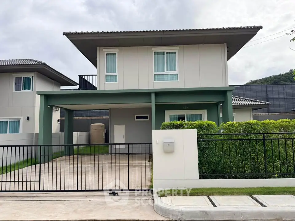 Modern two-story house with gated driveway and lush greenery in a serene neighborhood.