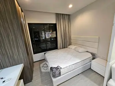 Modern bedroom with city view, featuring a cozy bed and sleek furnishings.