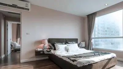 Modern bedroom with large window and stylish decor in a high-rise apartment.