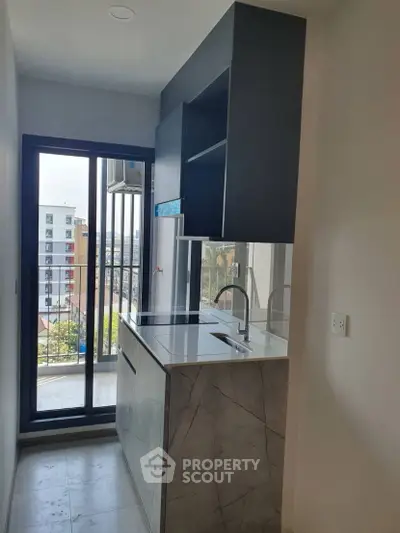 Modern compact kitchen with sleek design and city view balcony access.