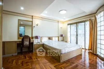 Spacious bedroom with elegant wooden flooring and large windows for natural light.
