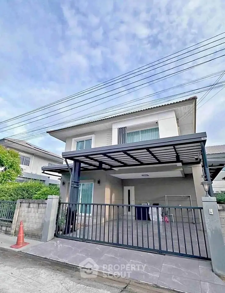 Modern two-story house with gated driveway and contemporary design in a suburban neighborhood.