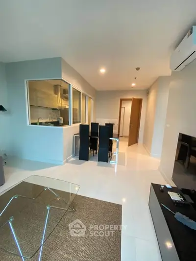 Modern living room with glass coffee table and dining area in open layout apartment.