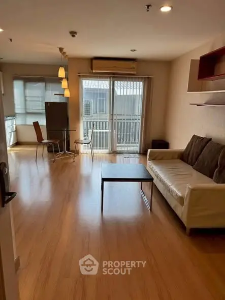Spacious living room with wooden flooring and balcony access in modern apartment.