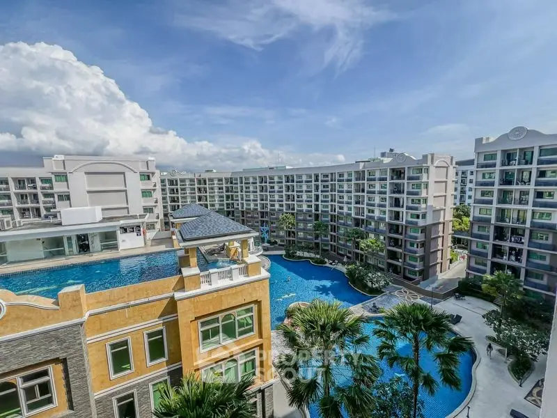Luxurious condominium complex with stunning pool and lush landscaping under a clear blue sky.