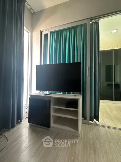 Modern living room with sleek TV stand and large windows for natural light.