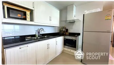 Modern kitchen with sleek white cabinets, stainless steel appliances, and black countertops.