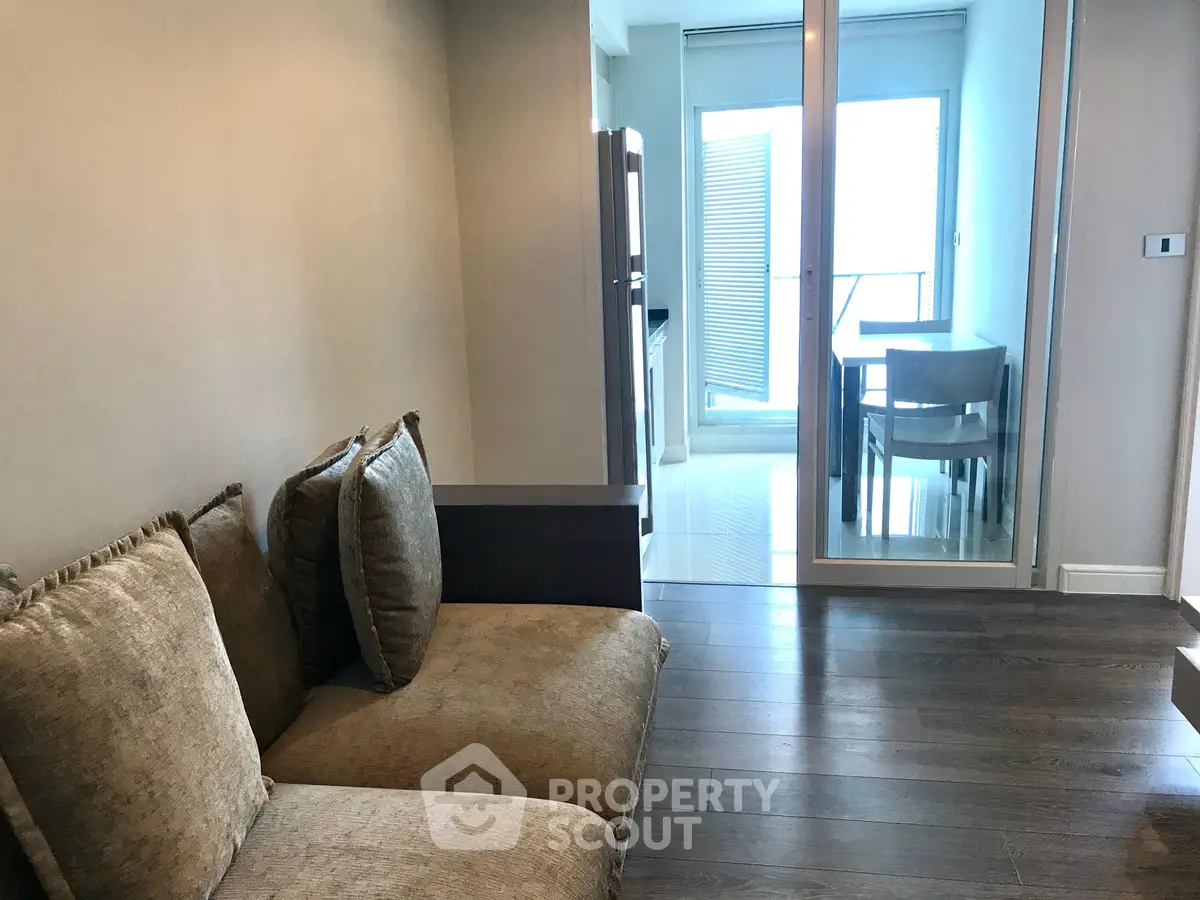 Modern living room with cozy seating and glass doors leading to a bright dining area.