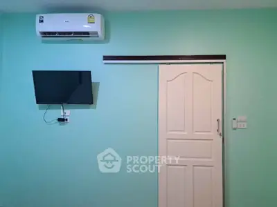 Minimalist room with air conditioning and wall-mounted TV, featuring a sliding door.