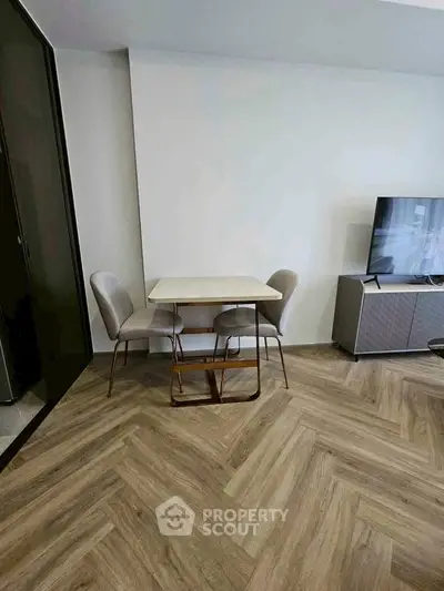Modern living room with stylish dining set and TV stand on herringbone floor.