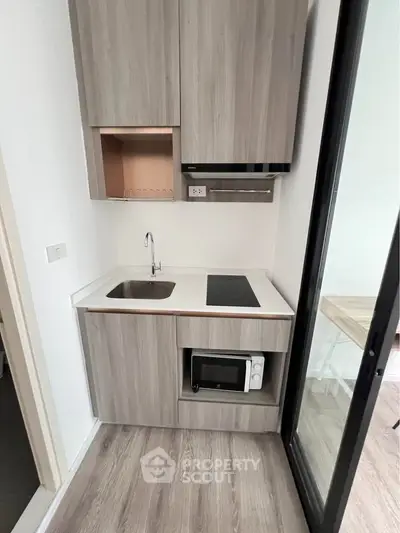 Modern compact kitchen with sleek cabinetry and built-in appliances in a stylish apartment.