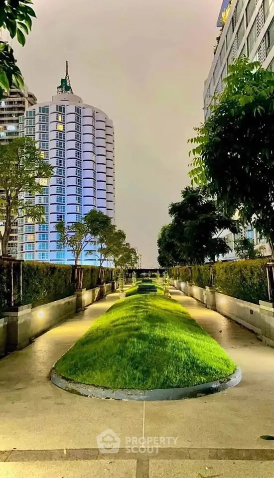 Luxurious garden pathway with modern high-rise buildings at night, perfect for urban living.