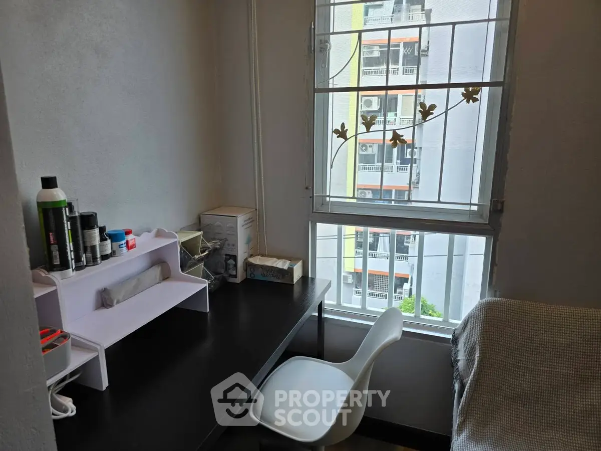 Cozy study nook with desk and chair, featuring a window view in a modern apartment.