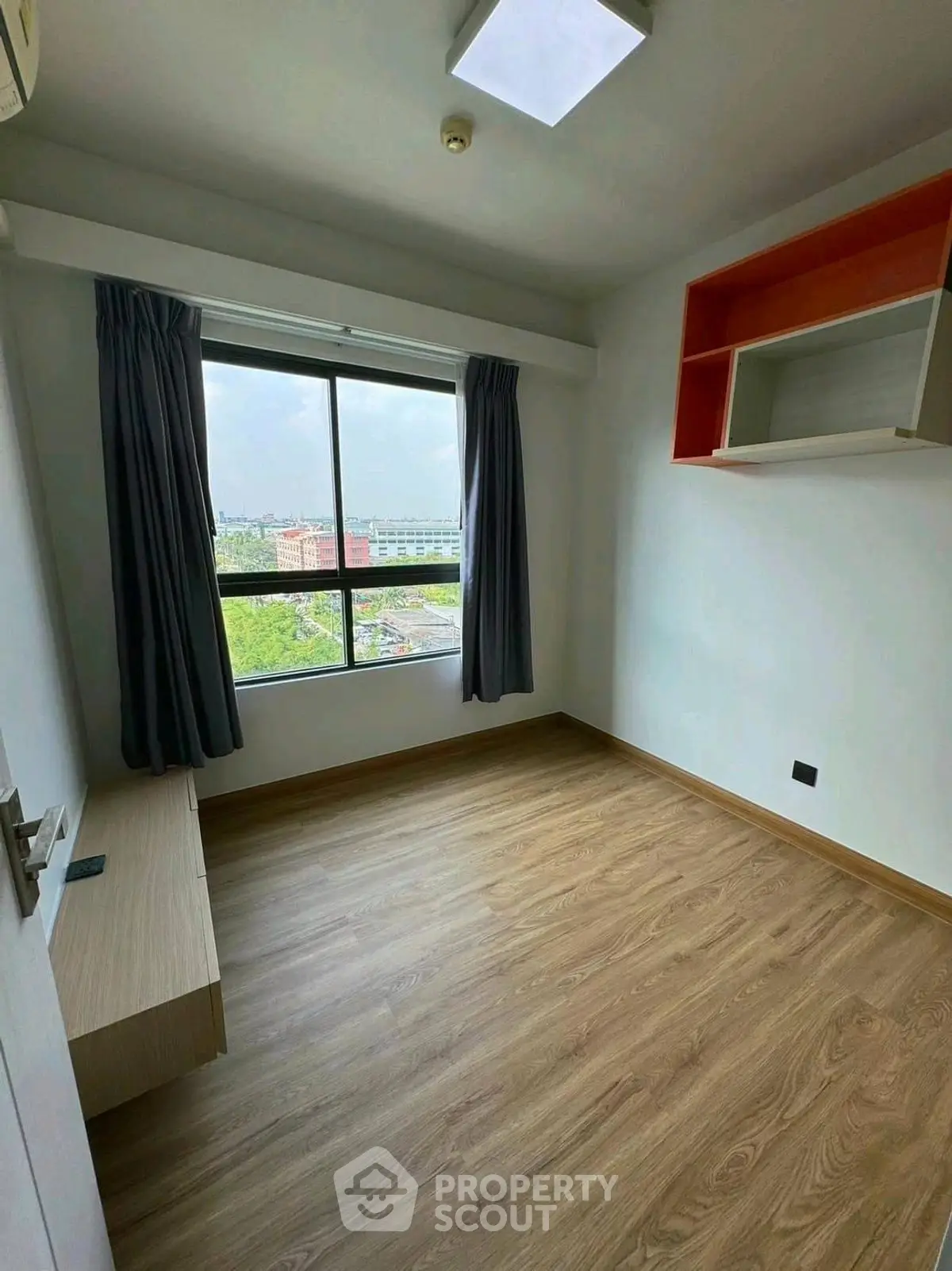 Bright empty room with large window and wooden flooring, ideal for customization.