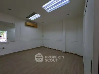 Spacious unfurnished room with wooden flooring and ceiling lights, ideal for customization.
