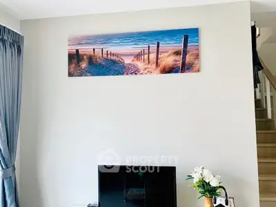 Modern living room with wall art and TV, featuring elegant decor and natural light.