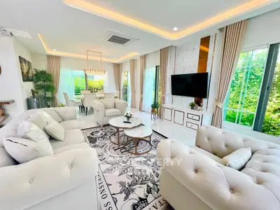 Luxurious living room with elegant decor and large windows offering lush garden views.
