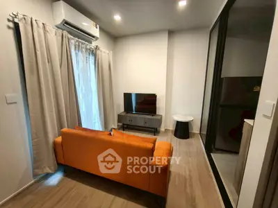 Modern living room with orange sofa, TV, and air conditioning in a cozy apartment setting.
