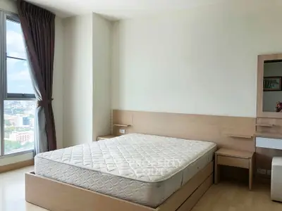 Spacious bedroom with large window offering city views, featuring a comfortable bed and modern furnishings.