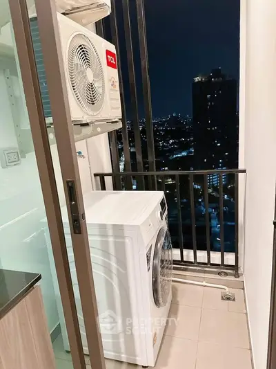 Compact balcony with washing machine and city night view, ideal for urban living.