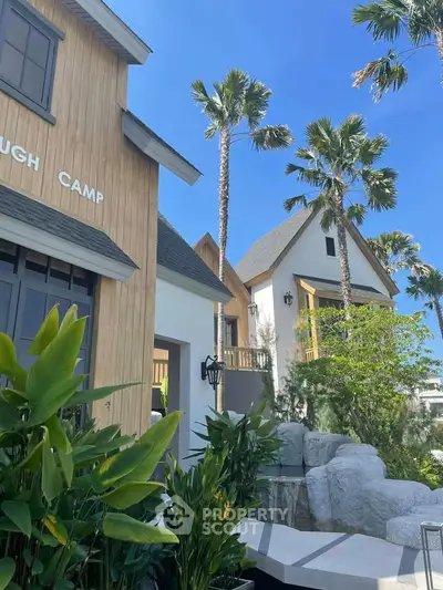 Charming modern cottages with lush landscaping and palm trees under a clear blue sky.