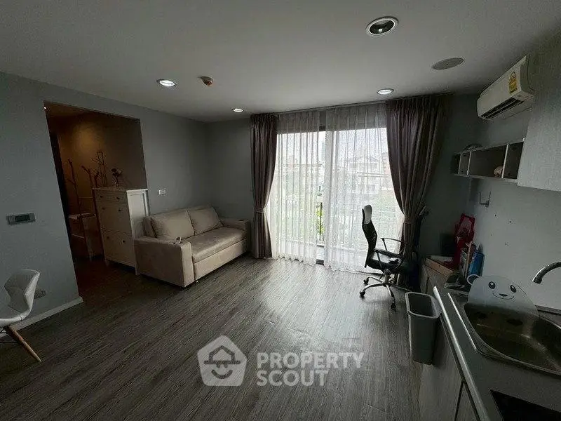 Modern living room with large window, sofa, and workspace in stylish apartment.