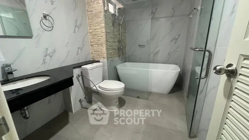 Modern bathroom with sleek design, featuring a freestanding bathtub and glass shower enclosure.