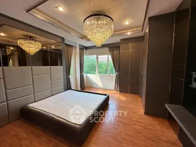 Luxurious bedroom with elegant chandelier and large windows offering scenic views.