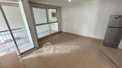 Spacious unfurnished living room with balcony access and modern fridge