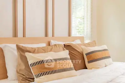 Cozy bedroom with stylish pillows and natural light through blinds.