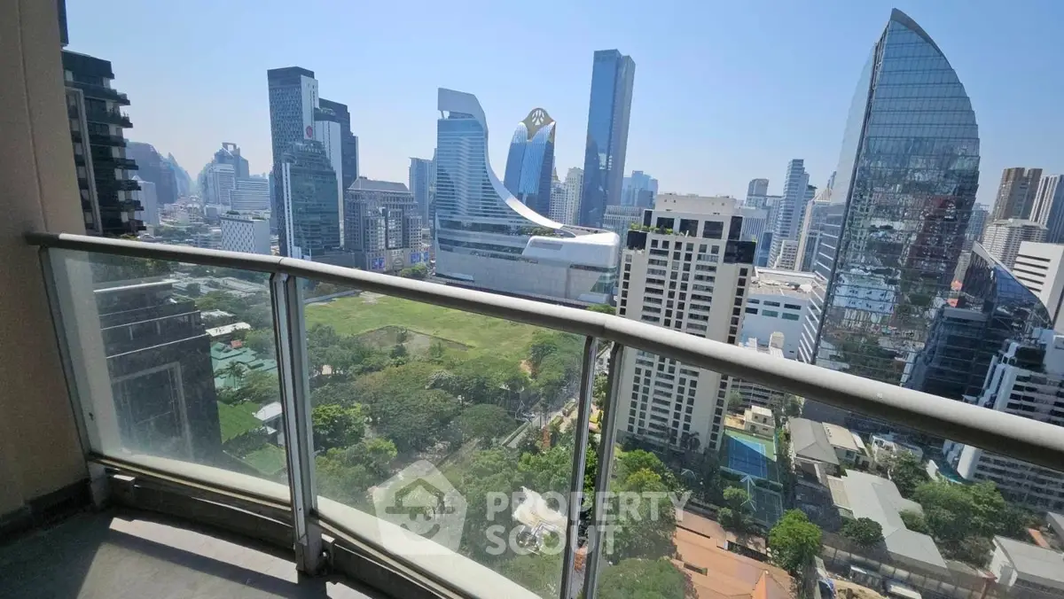 Stunning cityscape view from a high-rise balcony with modern skyscrapers and lush greenery.