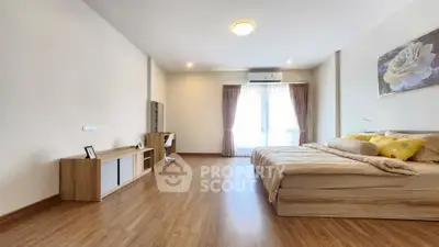 Spacious modern bedroom with wooden flooring and natural light
