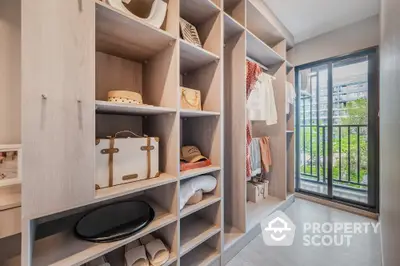 Luxurious walk-in closet with ample storage and balcony view in modern apartment.