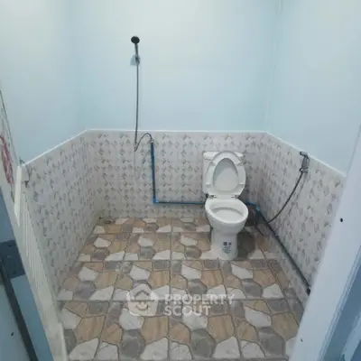 Simple bathroom with tiled floor and wall-mounted shower head.