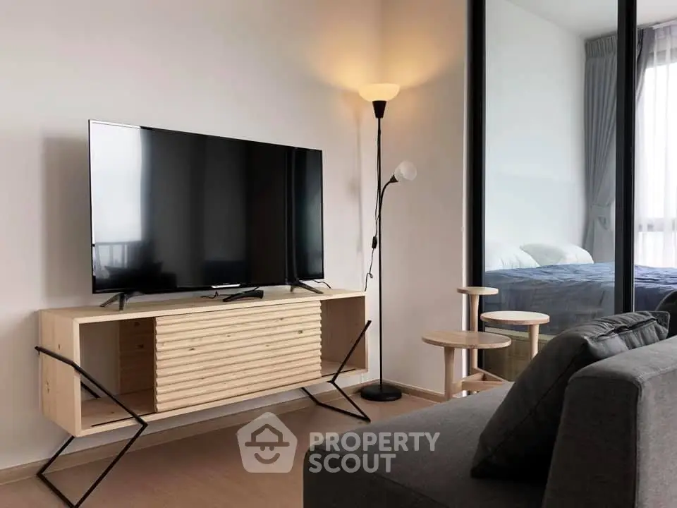 Modern living room with sleek TV setup and cozy bedroom view