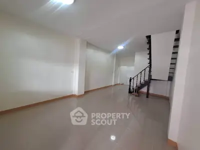Spacious empty living room with sleek staircase and glossy tiled floor
