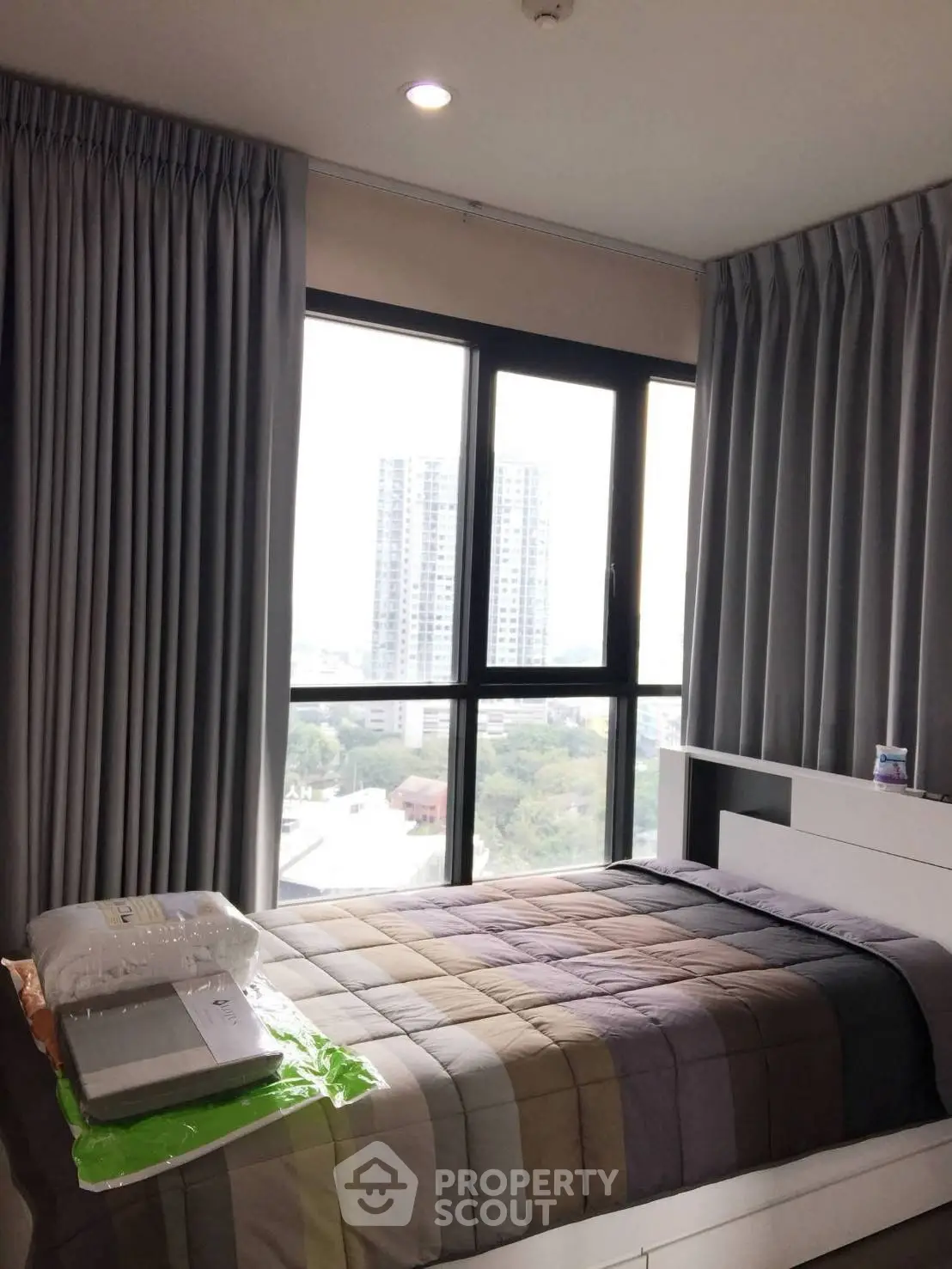 Modern bedroom with large window offering city view in high-rise apartment