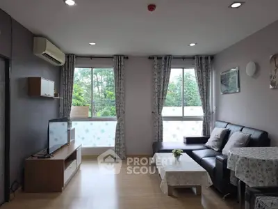 Modern living room with large windows and stylish decor, featuring a cozy seating area and natural light.