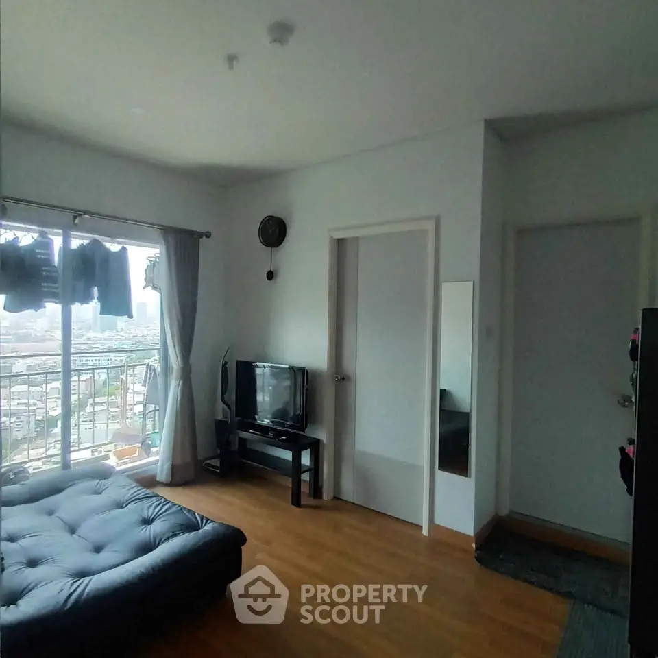 Modern living room with city view, featuring a cozy sofa and sleek TV setup.