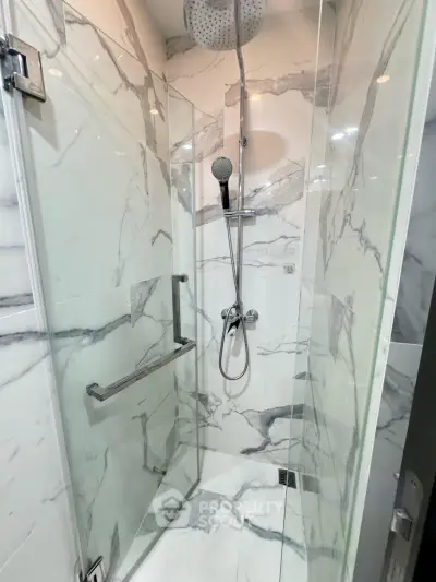 Luxurious marble-tiled shower with modern fixtures in a contemporary bathroom.