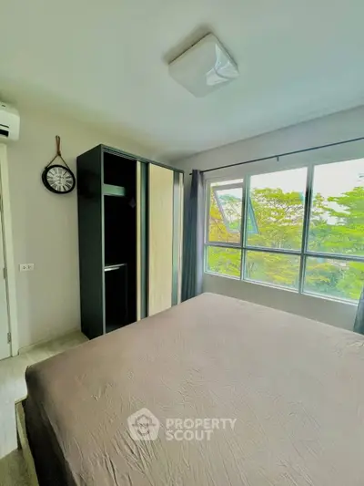 Bright bedroom with large window and modern wardrobe, offering serene garden views.