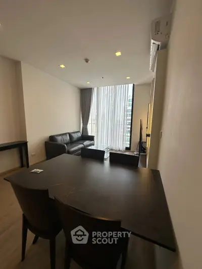 Modern living room with large windows and stylish furniture in a high-rise apartment.