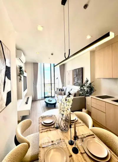 Modern open-plan living room with dining area, stylish decor, and large windows offering natural light.