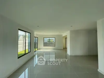 Spacious and bright open-plan living area with large windows and tiled flooring.